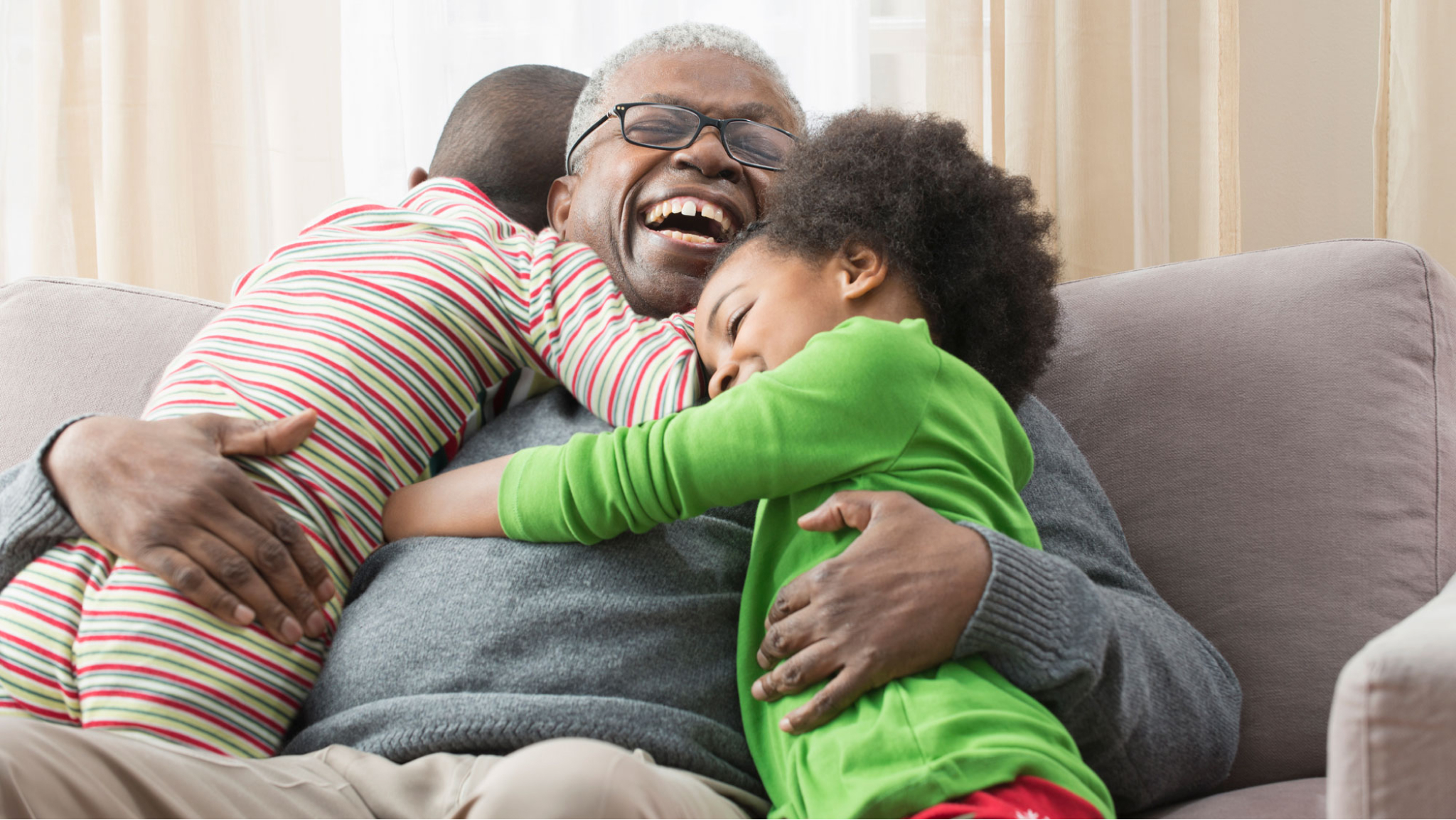 Smiling man hugging grandchildren